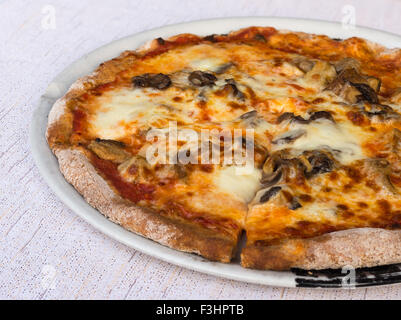 In the picture typical Italian pizza and slice cut out with tomato,mozzarella,cheese and mushrooms. Stock Photo