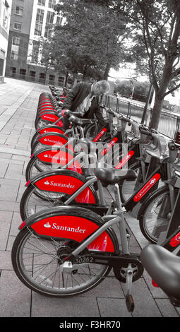 TFL London red rental hire bikes in Canary Wharf with new sponsor livery of Santander London UK ( B&W treatment) Stock Photo