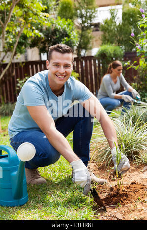 young man digging a hole before planting in home garden Stock Photo