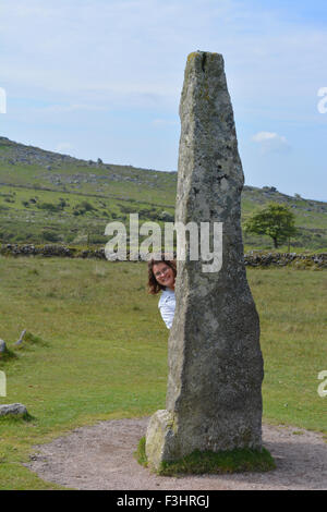 Teenage girl looking out from behind the Merrivale Standing Stone, Dartmoor National Park, Devon, England. Stock Photo