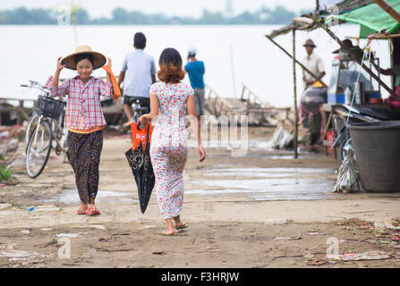 Two women, one on traditional worker’s clothing, the other in modern city attire, in Labutta, Myanmar. Stock Photo