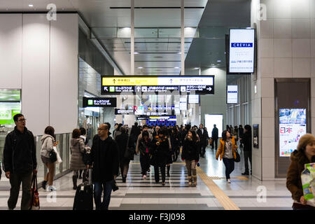 Osaka Station City interior. Commuters walking on concourse above platforms, overhead departure train information on display boards for each platform. Stock Photo