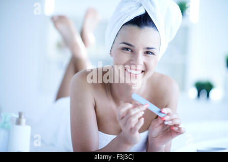 Pretty young woman taking care of her fingernails after bath Stock Photo