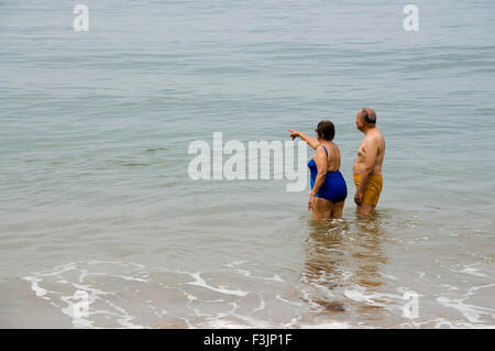 Senior couple standing in sea at Devbaug beach ; Sindhudurgh ; Maharashtra ; India Stock Photo