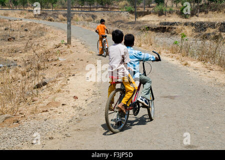 Two boys cycling on village road at Panvel taluka Maharashtra India Stock Photo