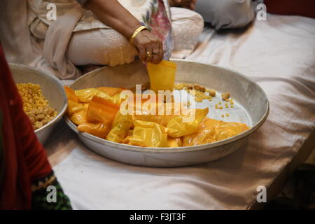 Indian Prasad  or religious offering is packed in yellow pack under big plate tray hold by hand Stock Photo