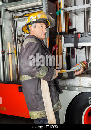 Fireman Fixing Water Hose In Truck At Fire Station Stock Photo