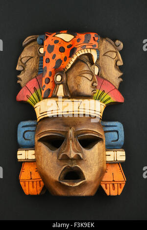 Indian Mayan Aztec wooden carved painted mask with roaring jaguar and human faces isolated on black paper background Stock Photo