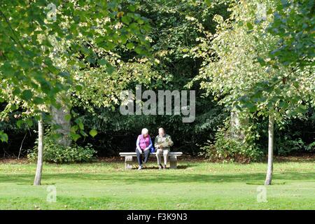Mature couple sitting on stone bench in parkland Stock Photo