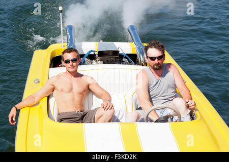 Two guys in a yellow and white speedboat in the sunshine on Lake Coeur d'Alene, ID. Stock Photo