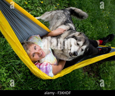 Happy girl with her dog resting in  hammock Stock Photo