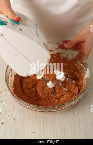 Making filling. Add chocolate mixture into whipped cream until just combined. Making Chocolate Hazelnut Meringue Cake Stock Photo