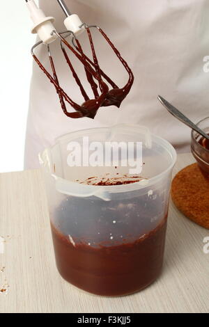 Making ganache. Pour melted chocolate into whipped cream until just combined. Making Chocolate Hazelnut Meringue Cake Stock Photo
