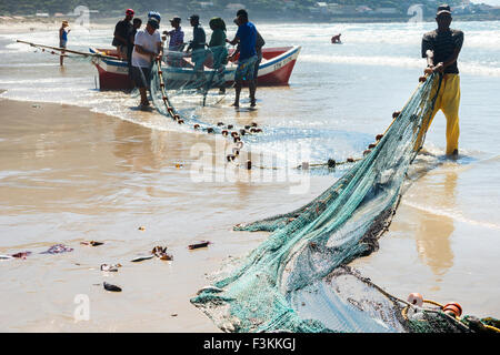 Trek fishermen surround their boat at the beach and pull up fishing nets on shore, Fishhoek Bay,  South Africa Stock Photo