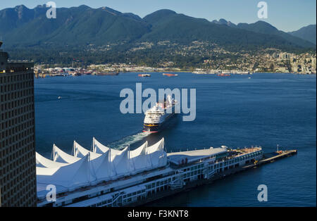 Disney Cruise ship departing from Canada Place in Vancouver harbour. Burrard Inlet and North Shore mountains. Stock Photo