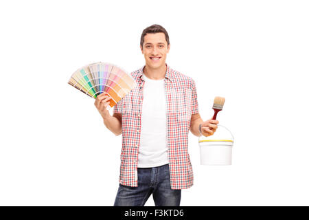 Studio shot of a cheerful young man holding a color swatch and a paintbrush isolated on white background Stock Photo