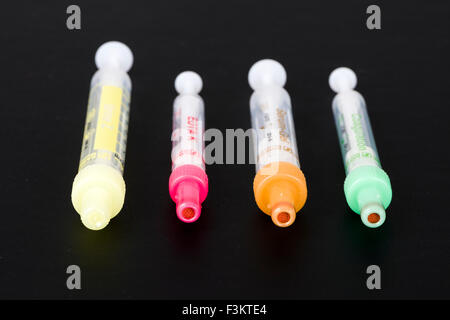 Four different pharmaceutical phials for medical use, displayed on a black table Stock Photo