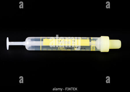 A yellow pharmaceutical phial for medical use, displayed on a black table Stock Photo