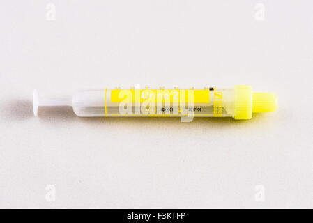 A yellow pharmaceutical phial for medical use, displayed on a white table Stock Photo