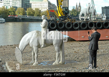 London, UK, 18 October 2015, 'The Rising Tide' horse sculptures in the Thames are removed. Sculpted by underwater sculptor Jason deCaires Taylor they have been commissioned to represent the part played by the river in the life of the city. The sculpture become submerged as the tide comes in. The arrogant businessmen on the horses represent the using up of the earths natural resources and the children the future that has to live with the consequences. Credit:  JOHNNY ARMSTEAD/Alamy Live News Stock Photo