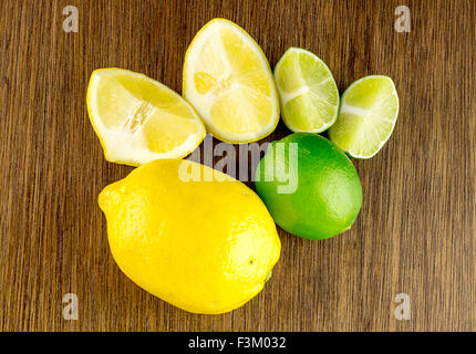 Overhead shot of vibrant ripe green limes and yellow lemons, cut and whole Stock Photo