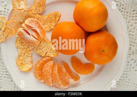 Juicy oranges on a white plate with peels Stock Photo