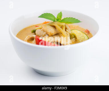 Capsicum, chicken, zucchini and carrots in Thai red curry with basil in a white bowl Stock Photo