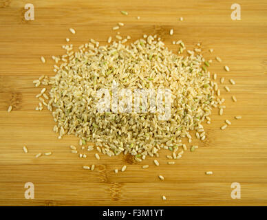 Uncooked brown rice pile on a wooden board Stock Photo