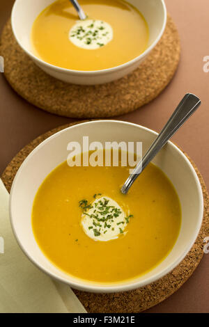 Hot pumpkin soup with cream and parsley garnish served in round ceramic bowls Stock Photo