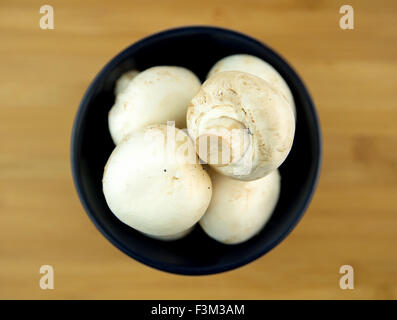 Pile of mushrooms in bowl on cutting board Stock Photo