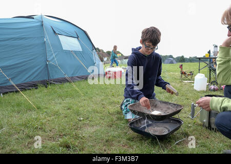 a young boy lights a barbecue with his mother watching on Stock Photo