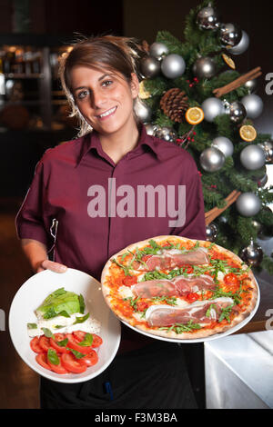 Waitress holding Parma pizza and Seafood Linguine, Strada, Italian chain restaurant, Covent Garden, London, England, UK Stock Photo