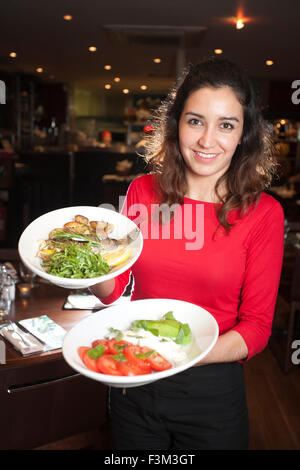 Waitress holding Caprese salad and Sea Bass, Strada, Italian chain restaurant, Covent Garden, London, England, UK Stock Photo