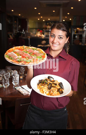 Waitress holding Parma pizza and Seafood Linguine, Strada, Italian chain restaurant, Covent Garden, London, England, UK Stock Photo