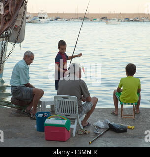 Men and boys fishing in a Spanish harbour. Stock Photo