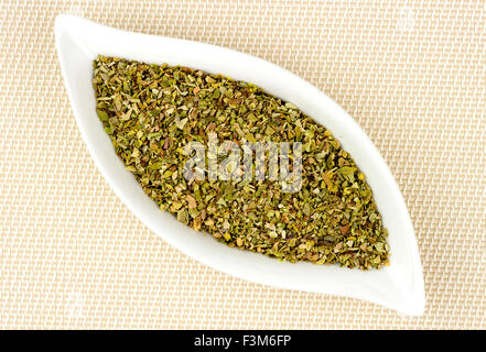 Dried and chopped oregano in stylish glass container Stock Photo