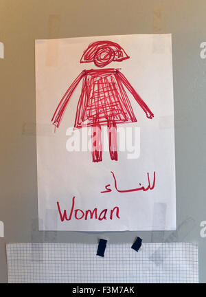 A sign with an illustration of a woman and text in both English and Arabic hangs at the toilet of a refugee processing centre in the public authorities headquaters in Potsdam, Germany, 9 October 2015. Brandenburg will be accepting more than 40,000 refugees after the orders of the Interior Minister. Photo: RALF HIRSCHBERGER/DPA Stock Photo
