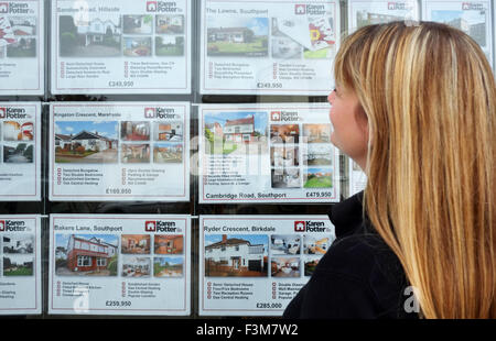 A woman looking estate agents window at domestic houses for sale on the market in Southport, Merseyside, UK Stock Photo