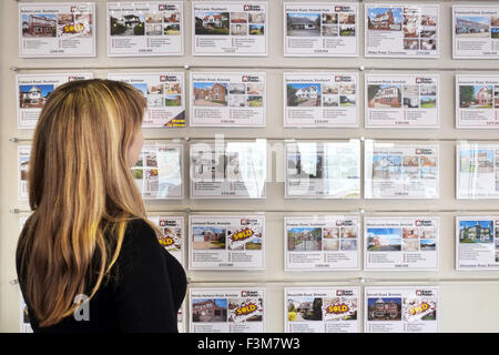 Property Brochures; A woman looking estate agents window at domestic houses for sale on the market in Southport, Merseyside, UK Stock Photo