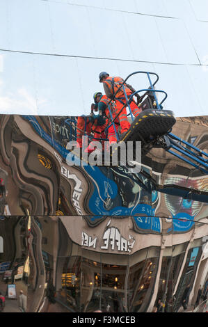 Birmingham, UK. 9th October, 2015. Workmen are seen against the mirrored surfaces of the Stephenson street entrance of the recently opened newly redeveloped New Street Station and Grand Central shopping centre. Credit:  Graham M. Lawrence/Alamy Live News.