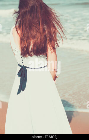 Historical young woman on the beach wearing a blue dress