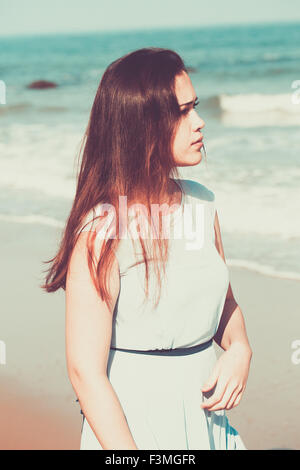 Historical young woman on the beach wearing a blue dress