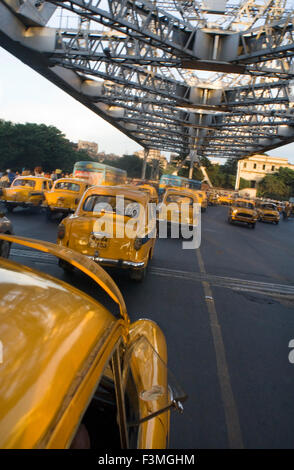 Yellow Ambassador taxis (cabs) crossing Howrah Bridge in Kokata (Calcutta), India. Kolkata, West Bengal, India. The taxi is one Stock Photo