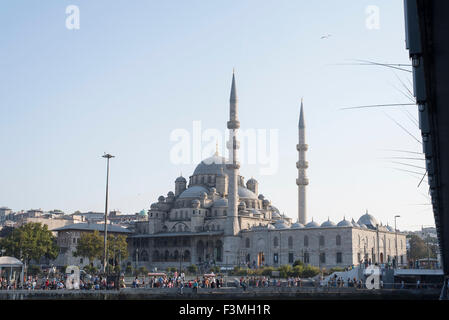 Fishermen fishing with rods from Galata bridge with the New Mosque in the background, Istanbul, Turkey. Stock Photo