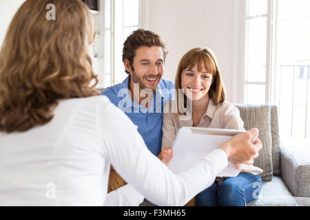 Architect presenting a new project on digital tablet to a cheerful young couple in office Stock Photo