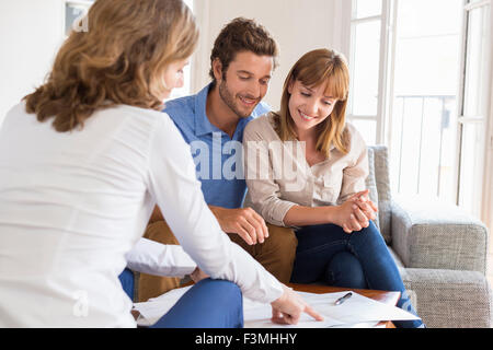 Real estate agent presenting a contract for house investment to future owners couple Stock Photo