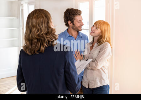 Real estate agent showing modern white apartment to future owners couple Stock Photo