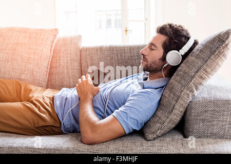 Man at home on sofa listening a music with a smartphone. Relaxe Stock Photo