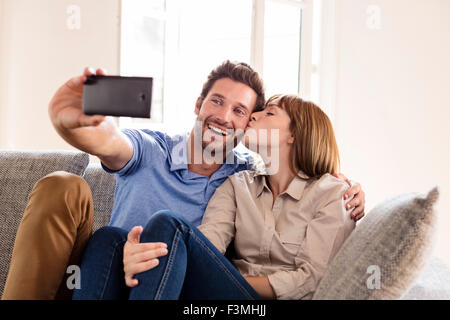 Couple in love taking a selfie with a mobile phone. it makes him a kiss Stock Photo
