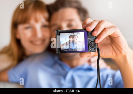 Cheerful couple taking a selfie with a camera. White home background Stock Photo